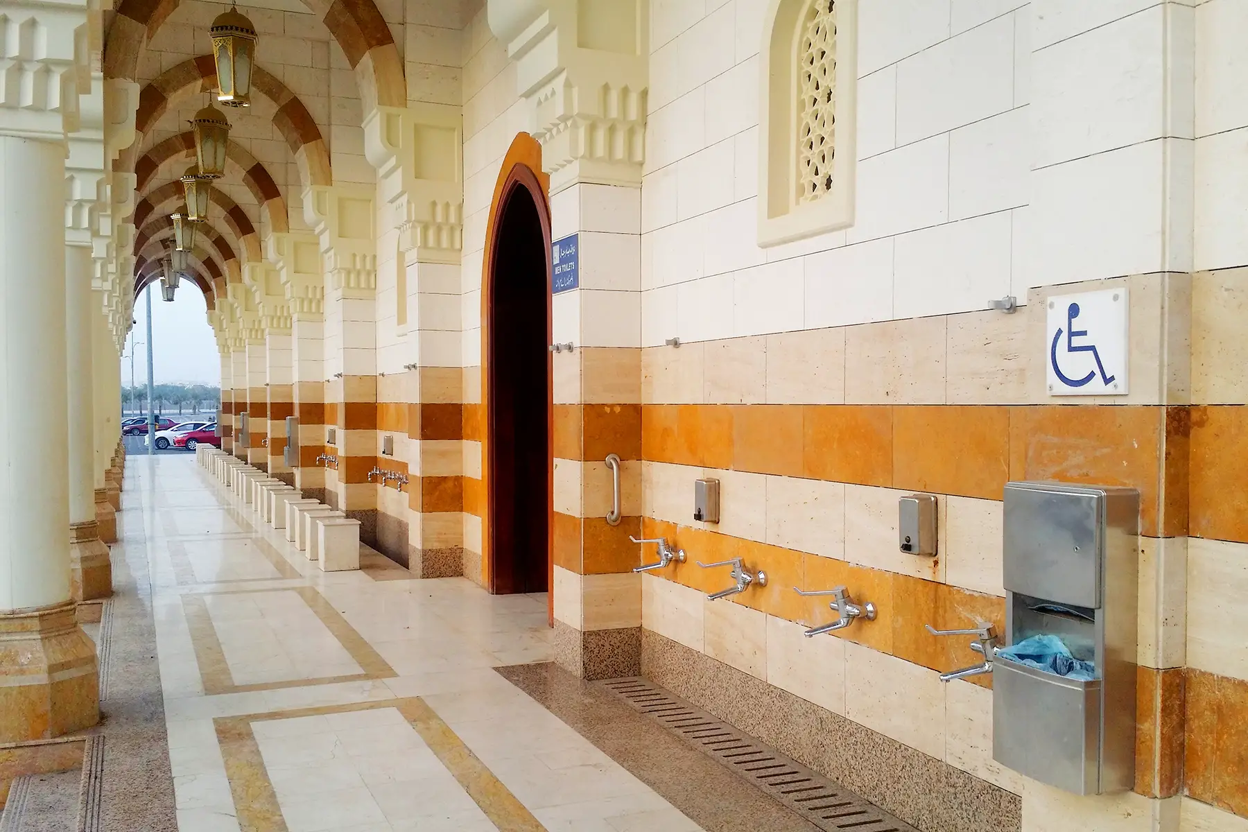 Faucets for washing outside a mosque, with a disabled sign outside