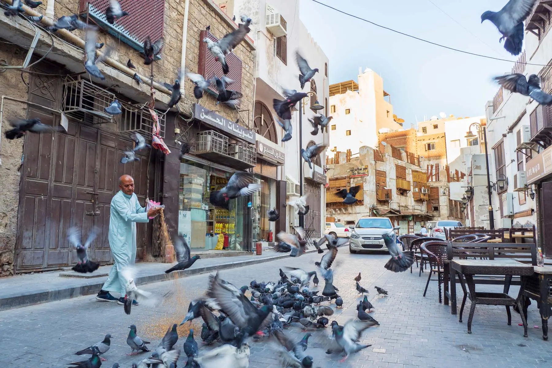 man feeding pigeons on street in Saudi Arabia