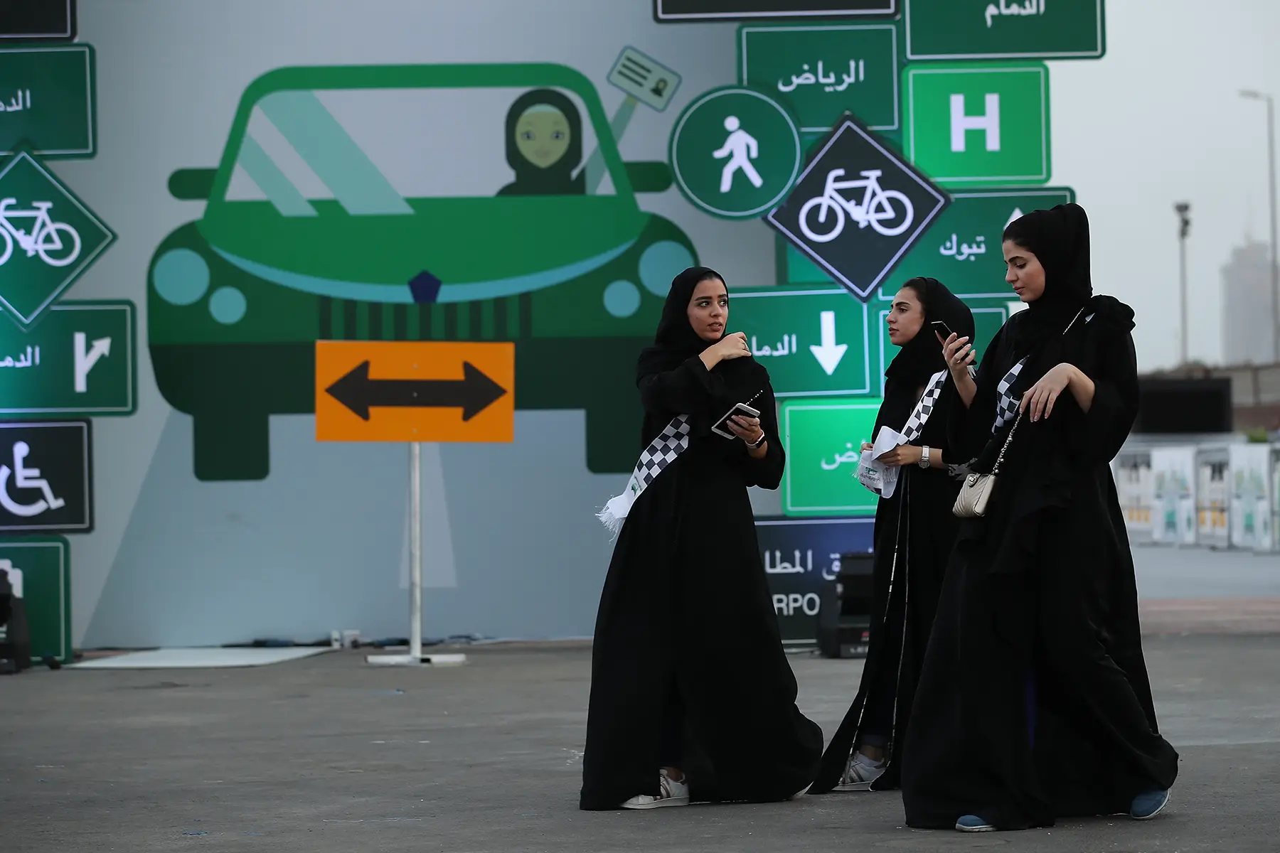 A group of three women in abayas outside a driving school