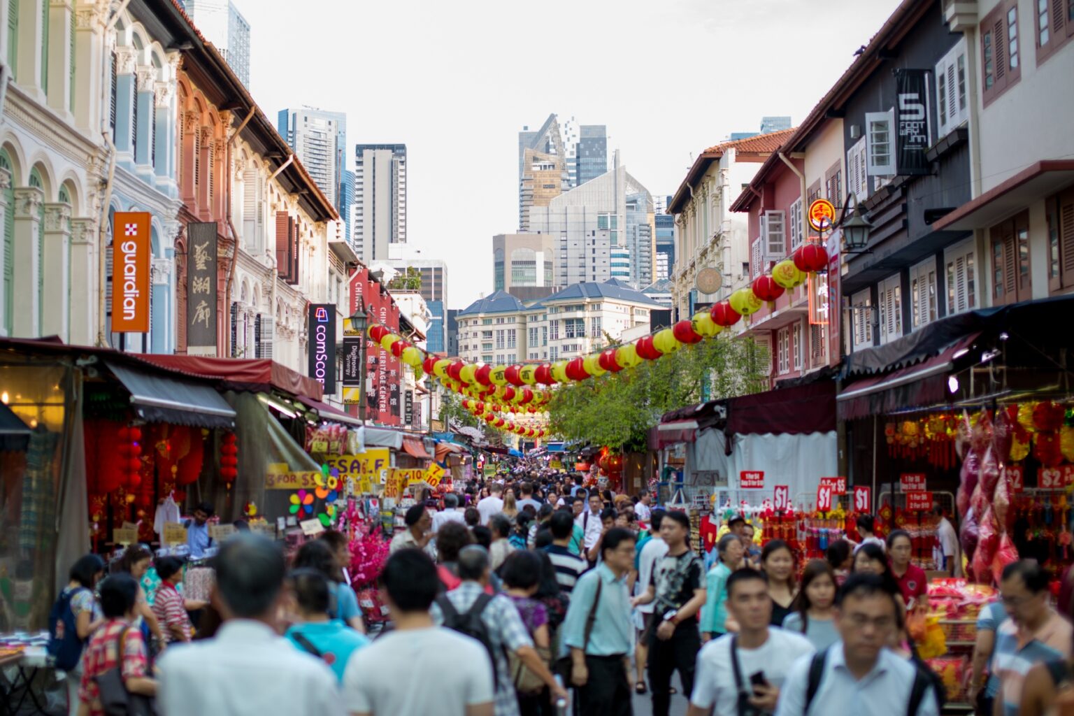 Crowds of people walk down a street lined with Chinese New Year decorations and stalls