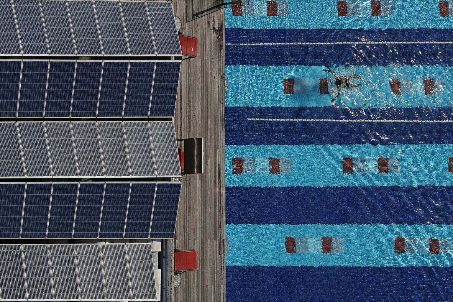 Swimming pool next to a building with solar panels on the roof