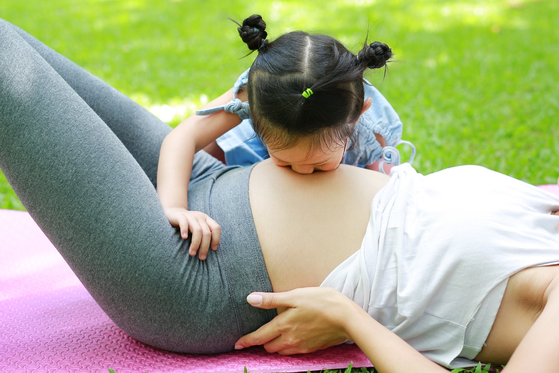 Young girl kissing a pregnant belly