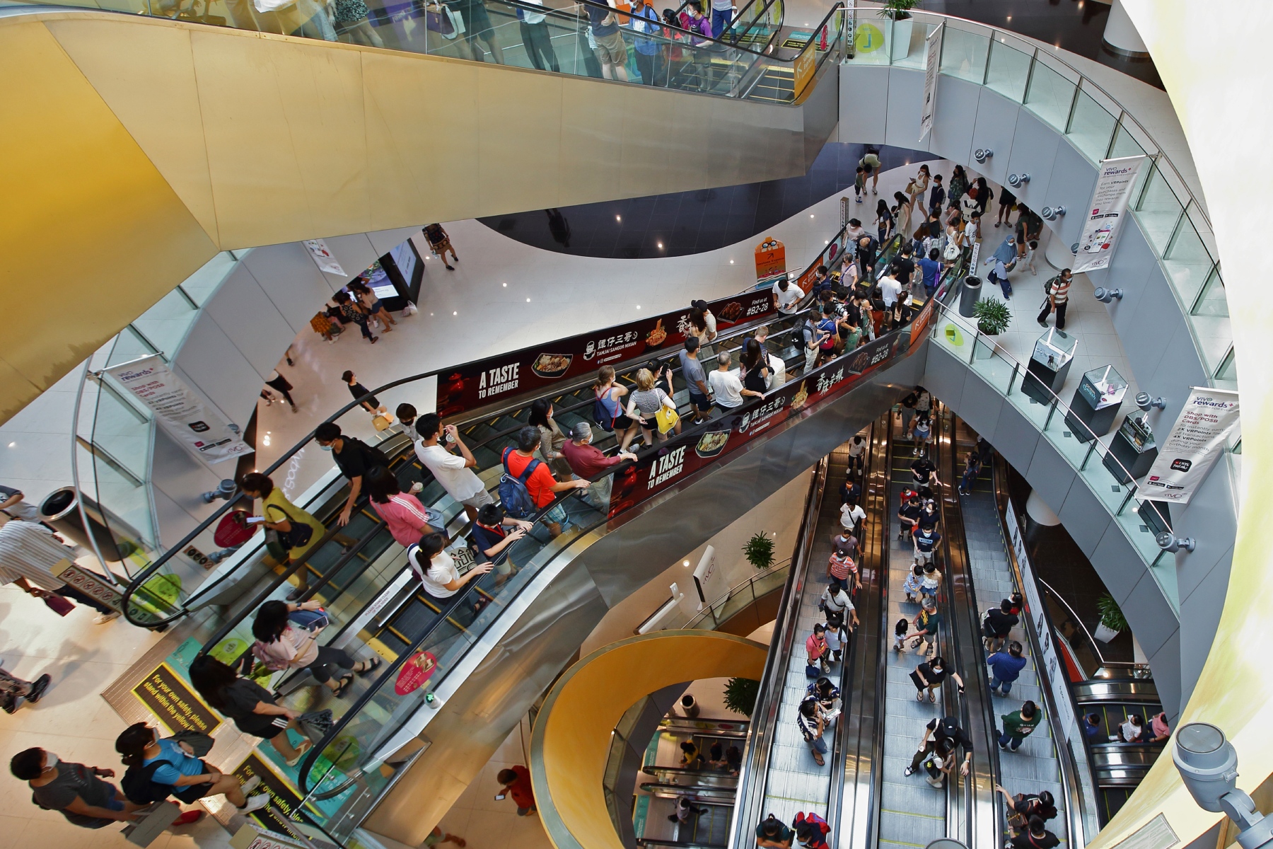 Crowds of people ride an escalator in a shopping mall in Singapore