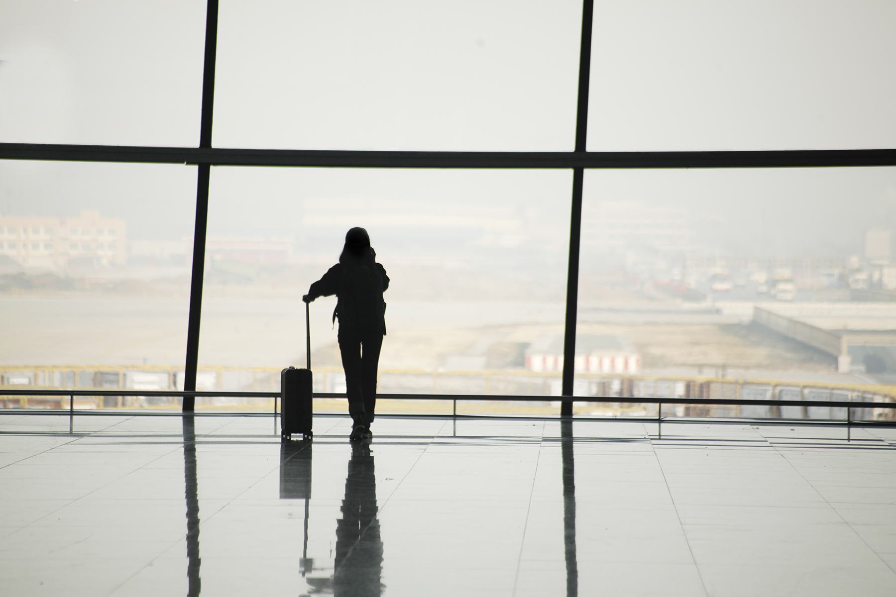 Silhouette of traveler in airport at large window