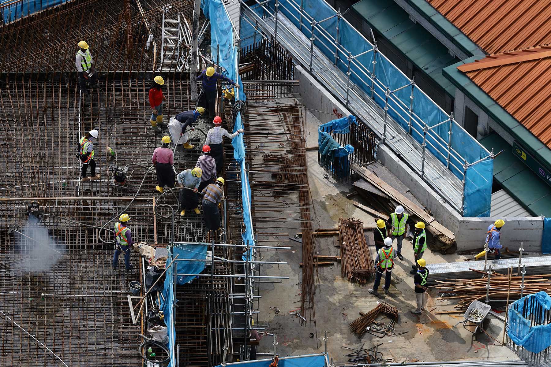 Migrant laborers work at a building construction site in Singapore.