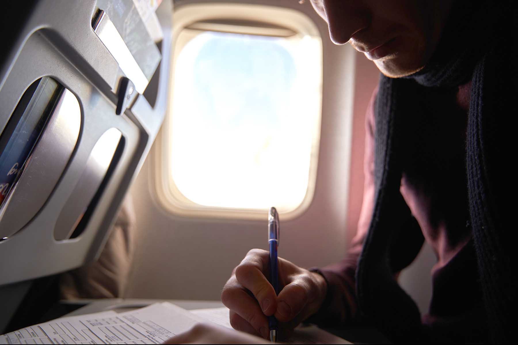 Man filling out information on an immigration form, while still on the plane.