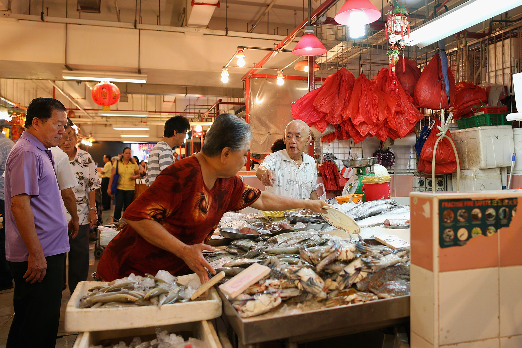 Customers buying fresh fish at a stall in the Chinatown Complex Wet Market in Singapore