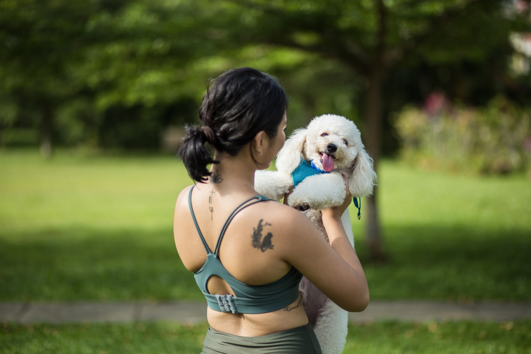 A woman in athleisure holds her smiling dog in a park