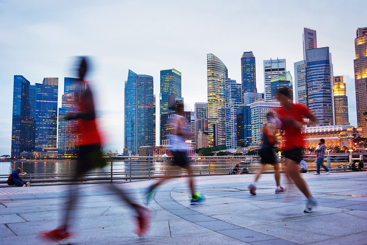 Blurry people running on the boulevard, with Singapore skyscrapers in the background