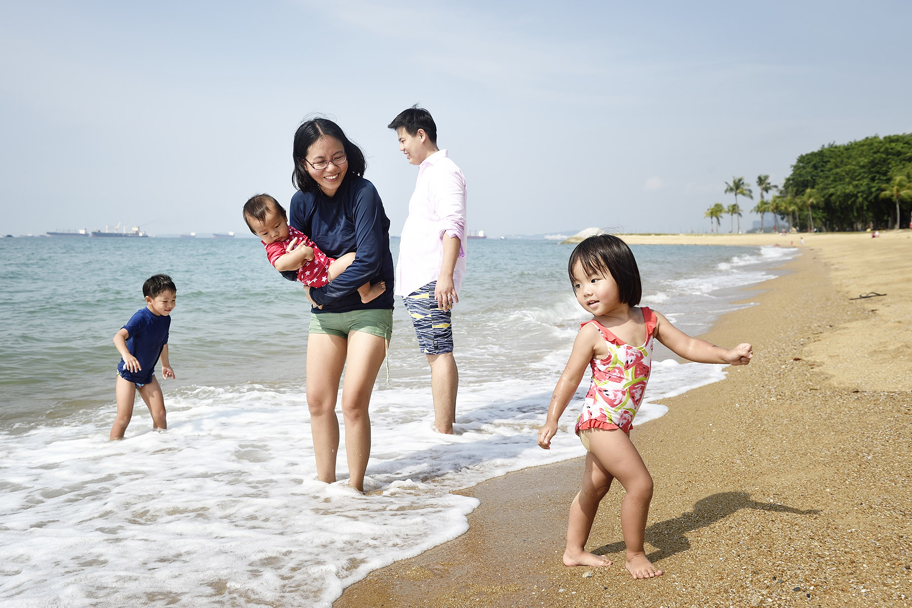 A family of four playing on an empty beach in the water