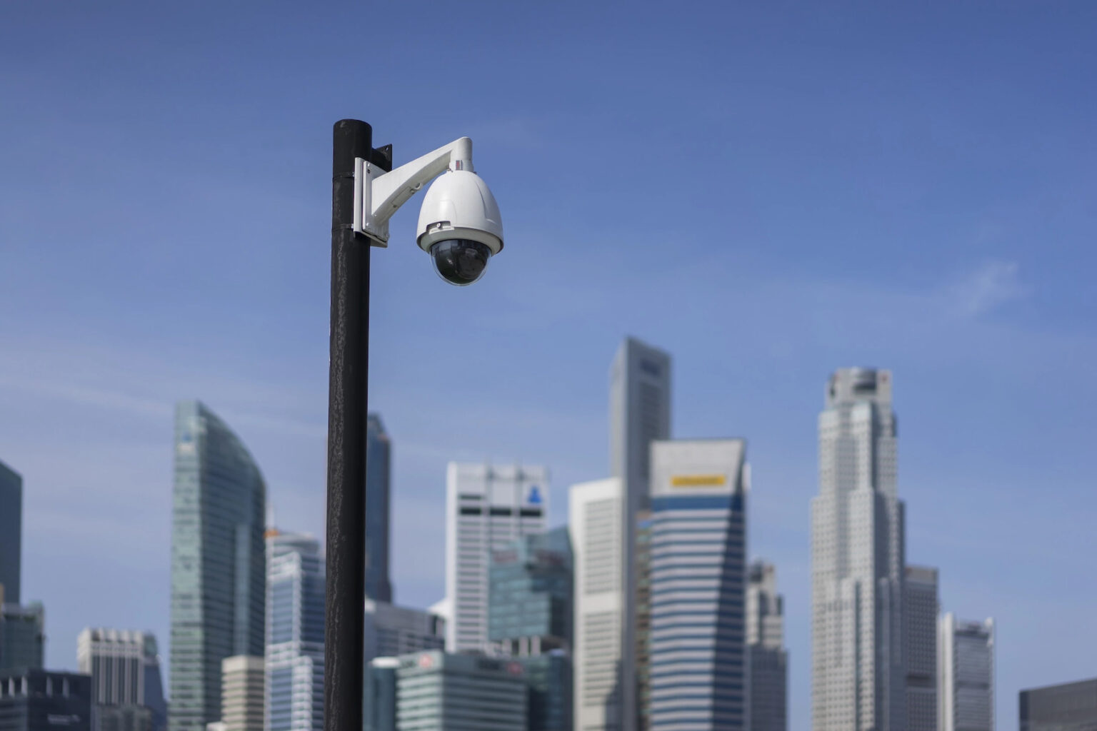 Street CCTV camera mounted on a pole - Singapore high rises in background