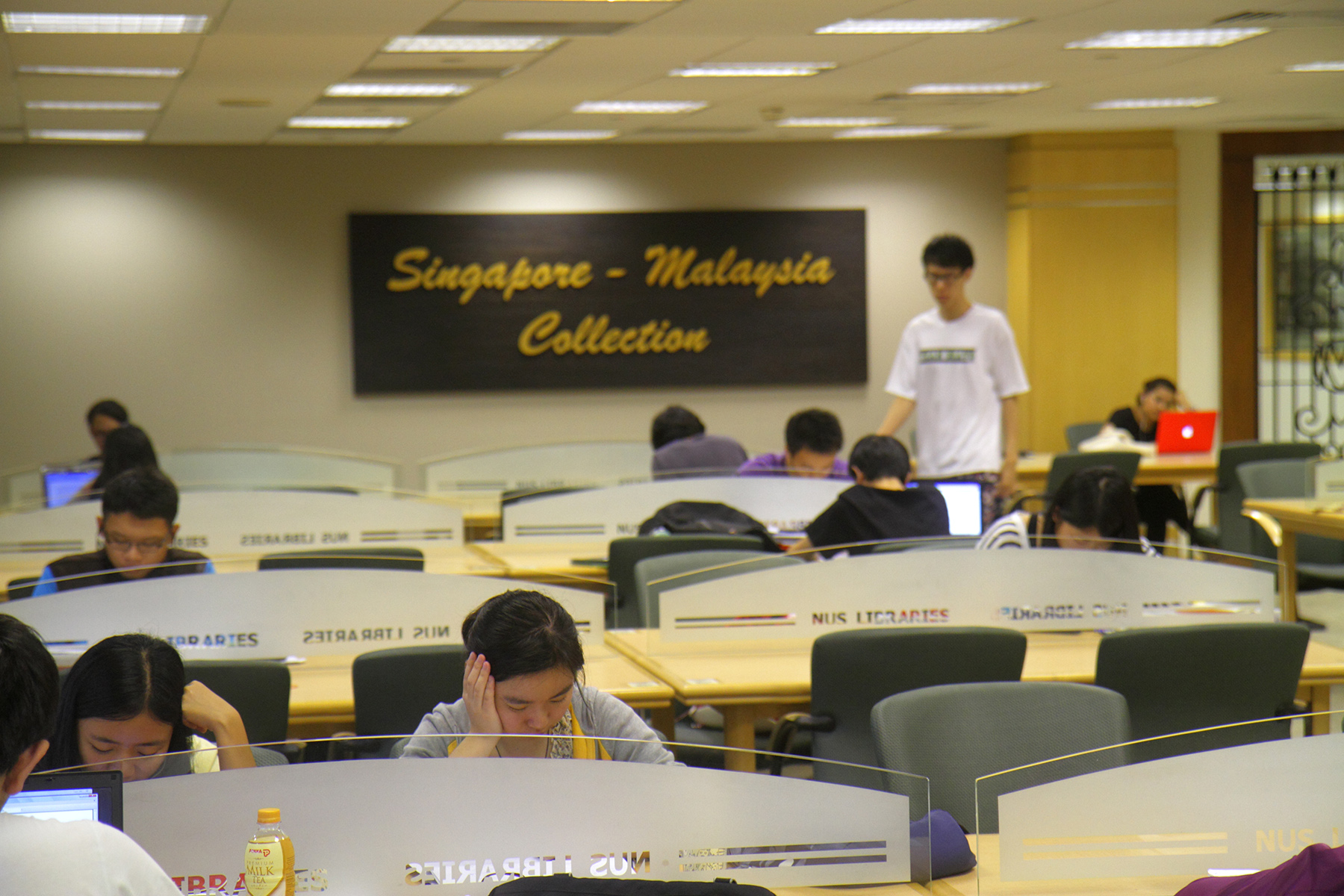Group of students studying at tables with laptops, Central Library at the National University of Singapore