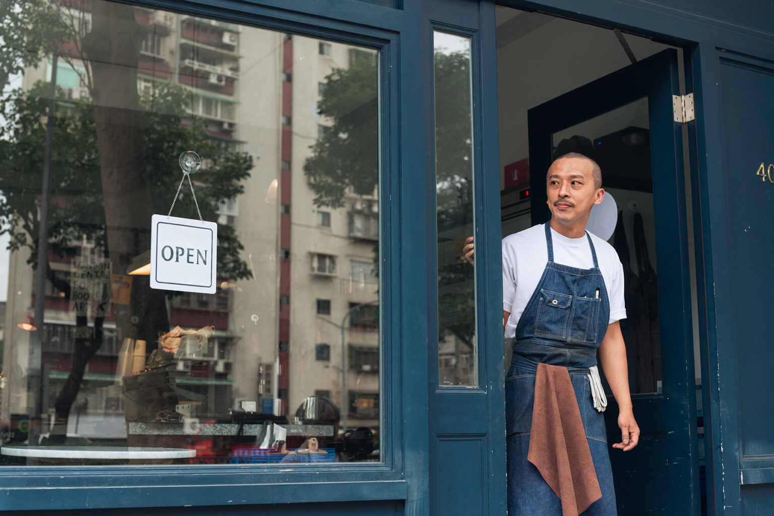 A business owner looks out the door onto the street as he opens his shop for the day