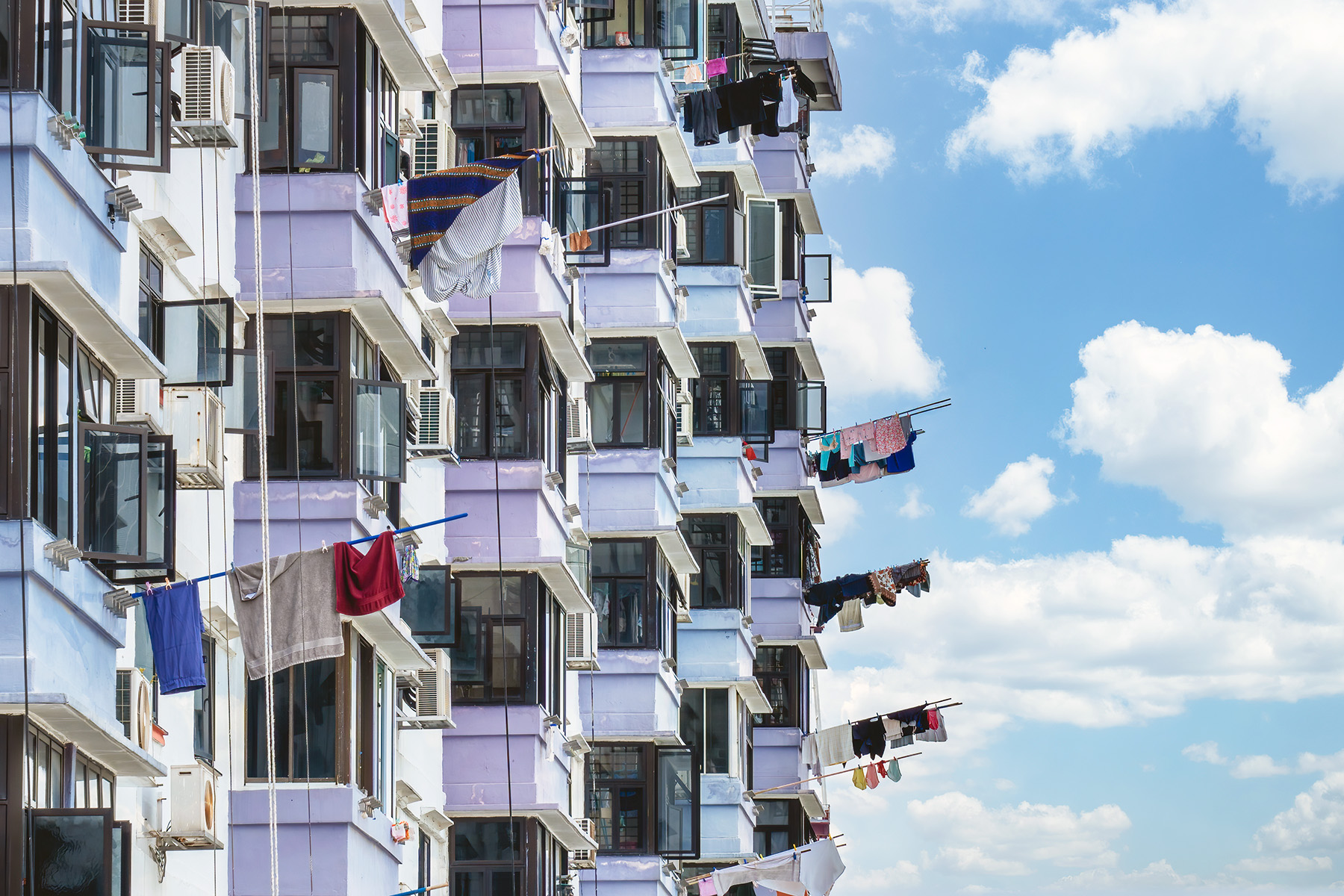 People in high building hanging clothes from their window on a pole.