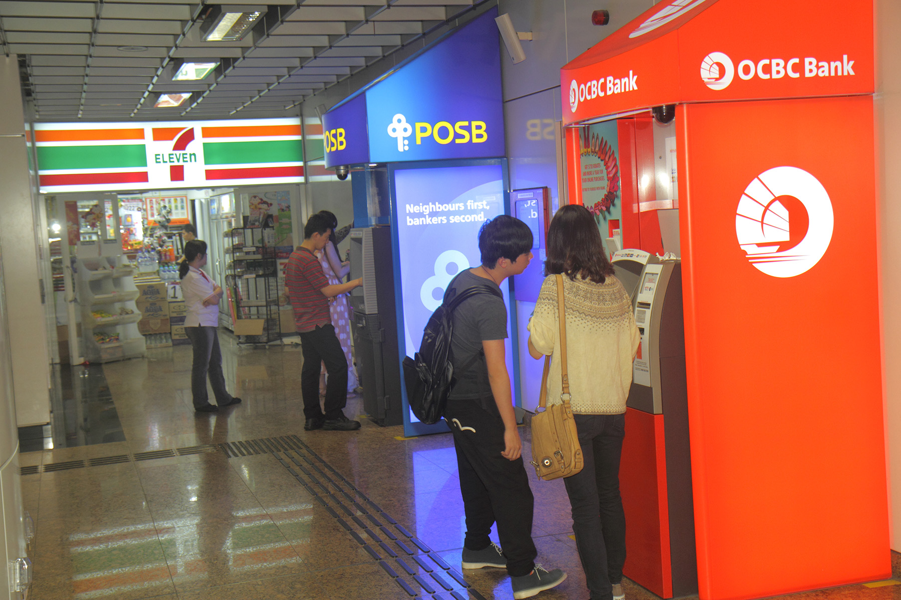 People drawing money at various ATMs from their Singapore bank account