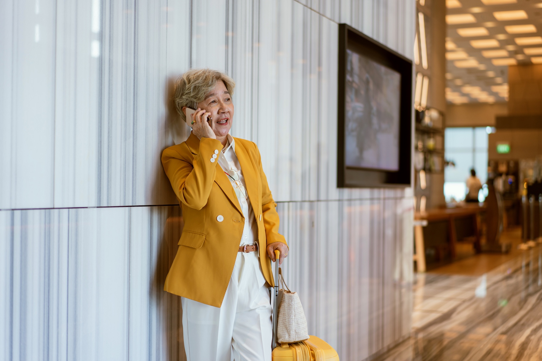 An older businesswoman waits for her flight at the airport while taking a phone call