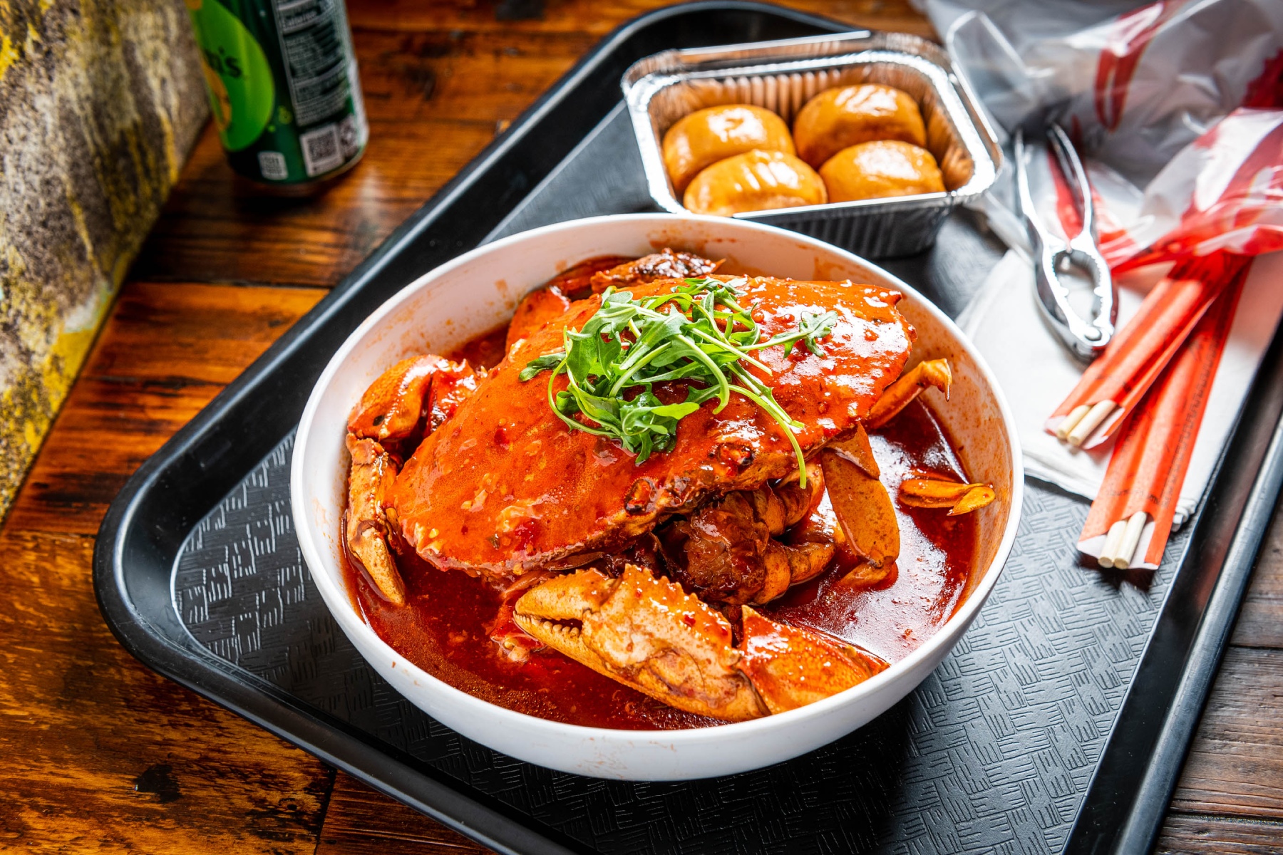 Chili crab in a plate on a serving tray with a side of steamed buns (mantou)