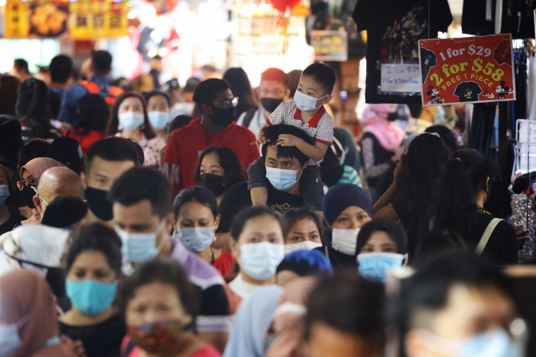 A crowded Singapore street in a market district where everyone is wearing a protective face mask
