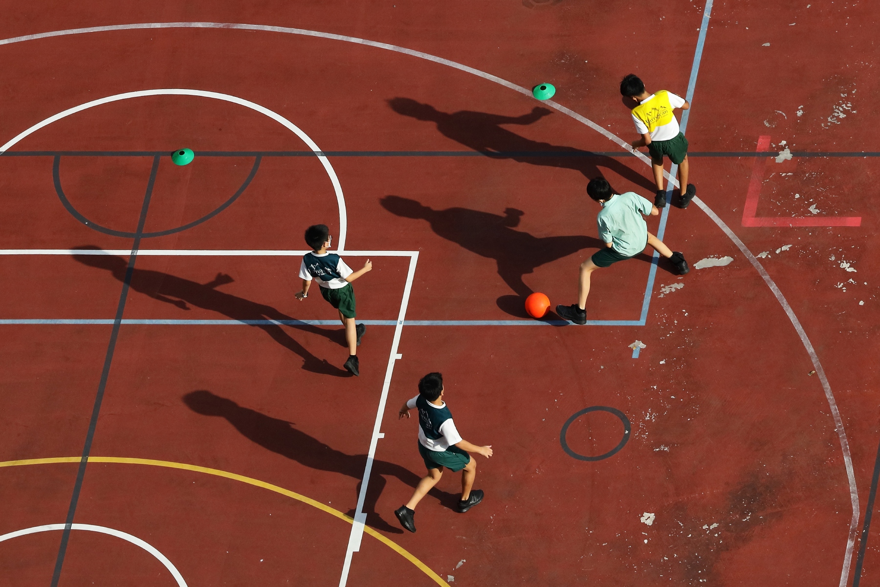 Secondary school students play football on a sports court
