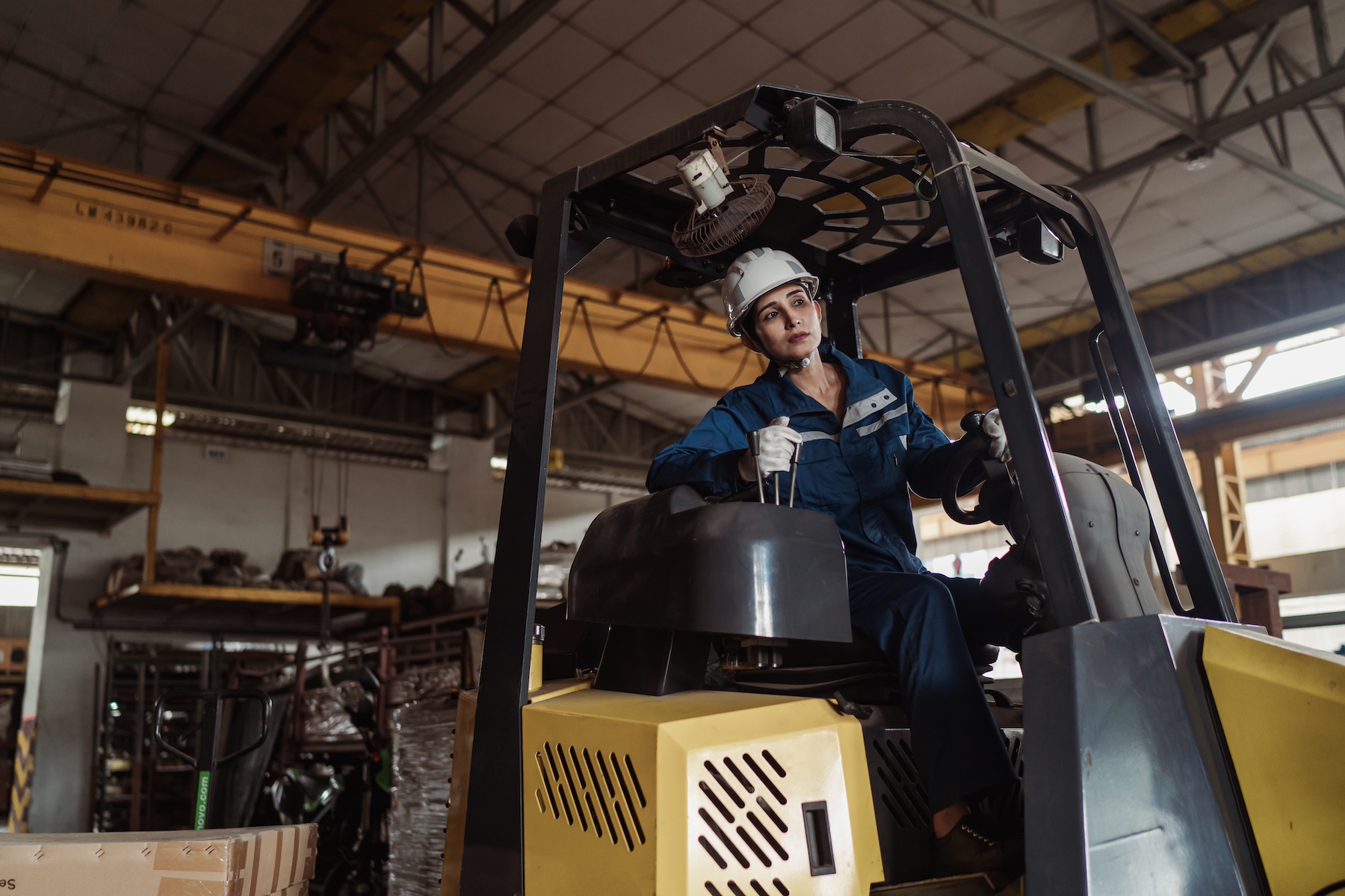 A warehouse worker drives a forklift in safety gear