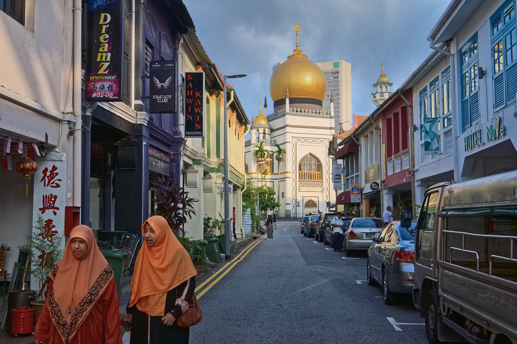 Women walking down the street in Kampong Glam, with the Sultan Mosque in the background.
