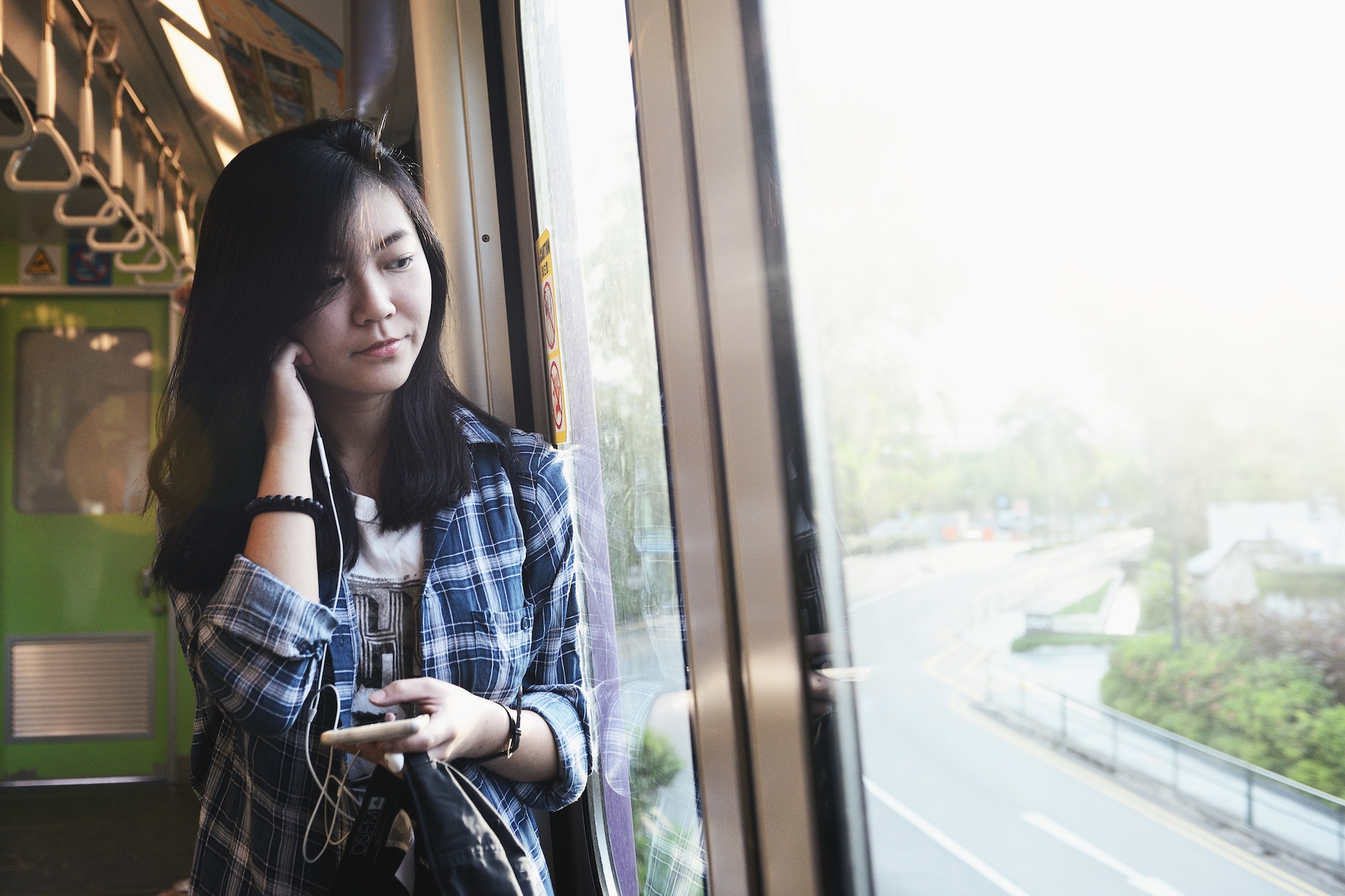 Young woman on the phone while looking out the window in Singapore's Sentosa LRT