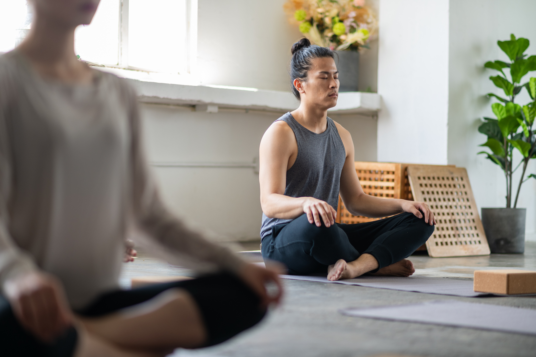 A man sits peacefully on the floor in yoga class with his eyes closed
