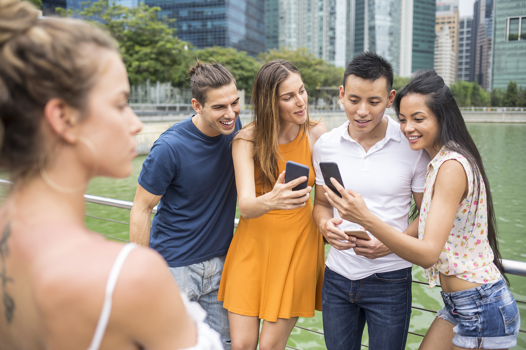A group of young people looking at something on their mobile phone during their first week in Singapore