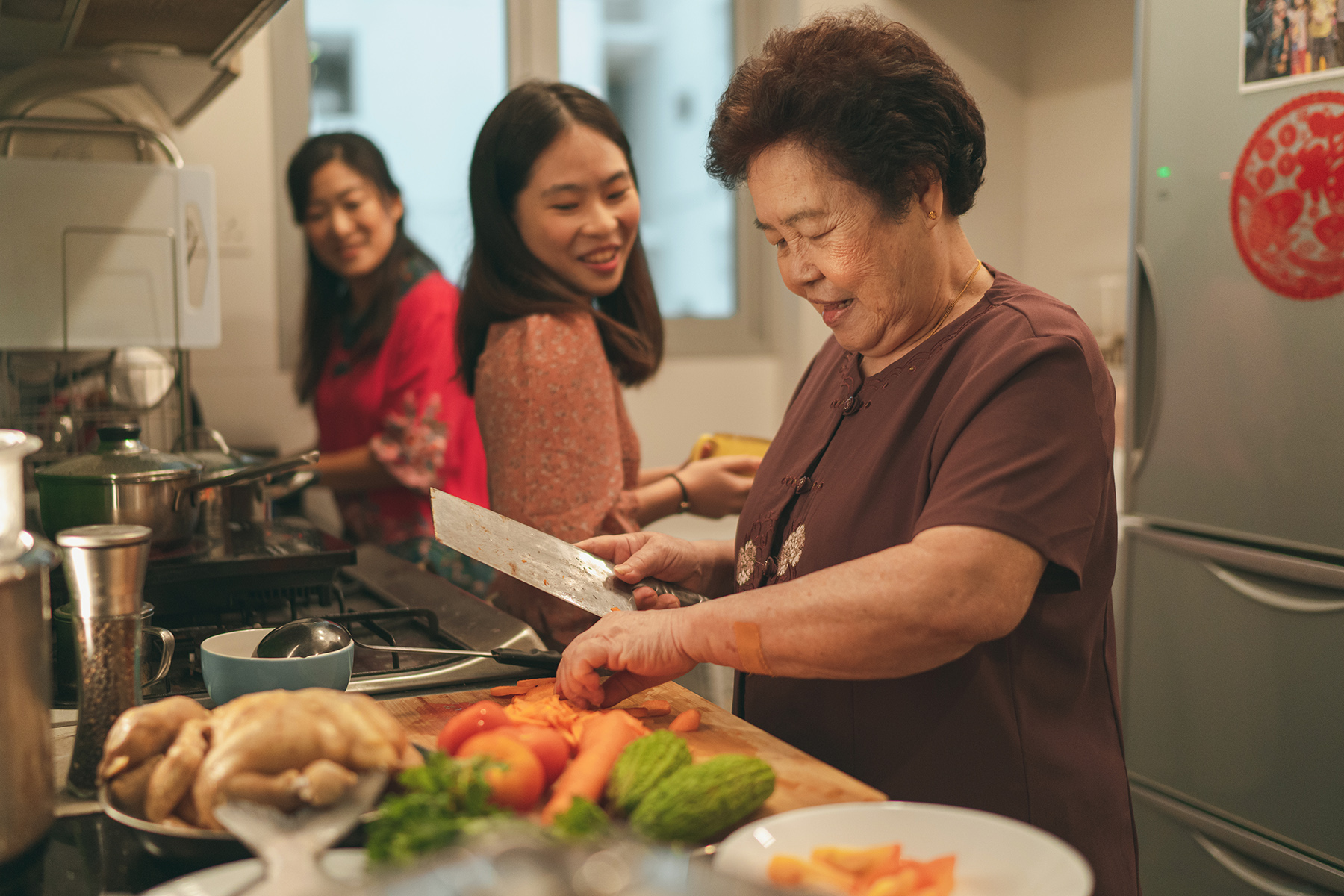 A grandmother cooking with her granddaughter and daughter in the kitchen
