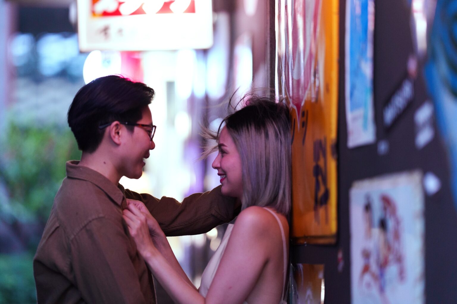A lesbian couple stand closely and look at each other in an illuminated street