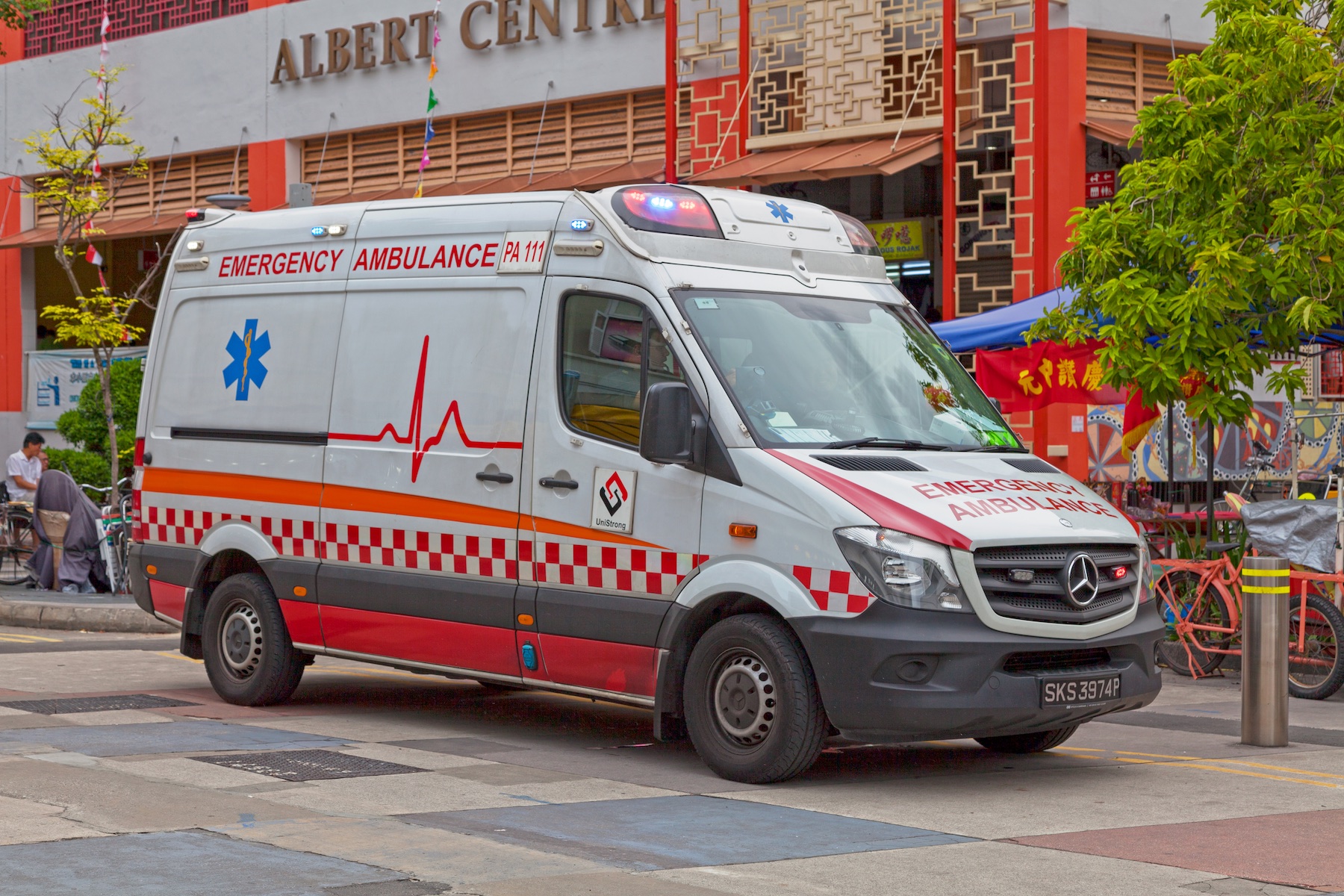An ambulance is parked on the street outside a shopping center
