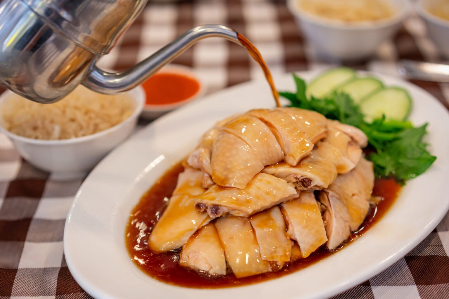 Spout pouring sauce on Hainanese steamed chicken at restaurant