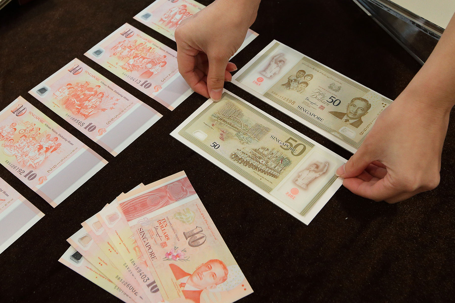 Person is displaying Singapore's commemorative banknotes to mark Singapore's 50 years of nation-building.