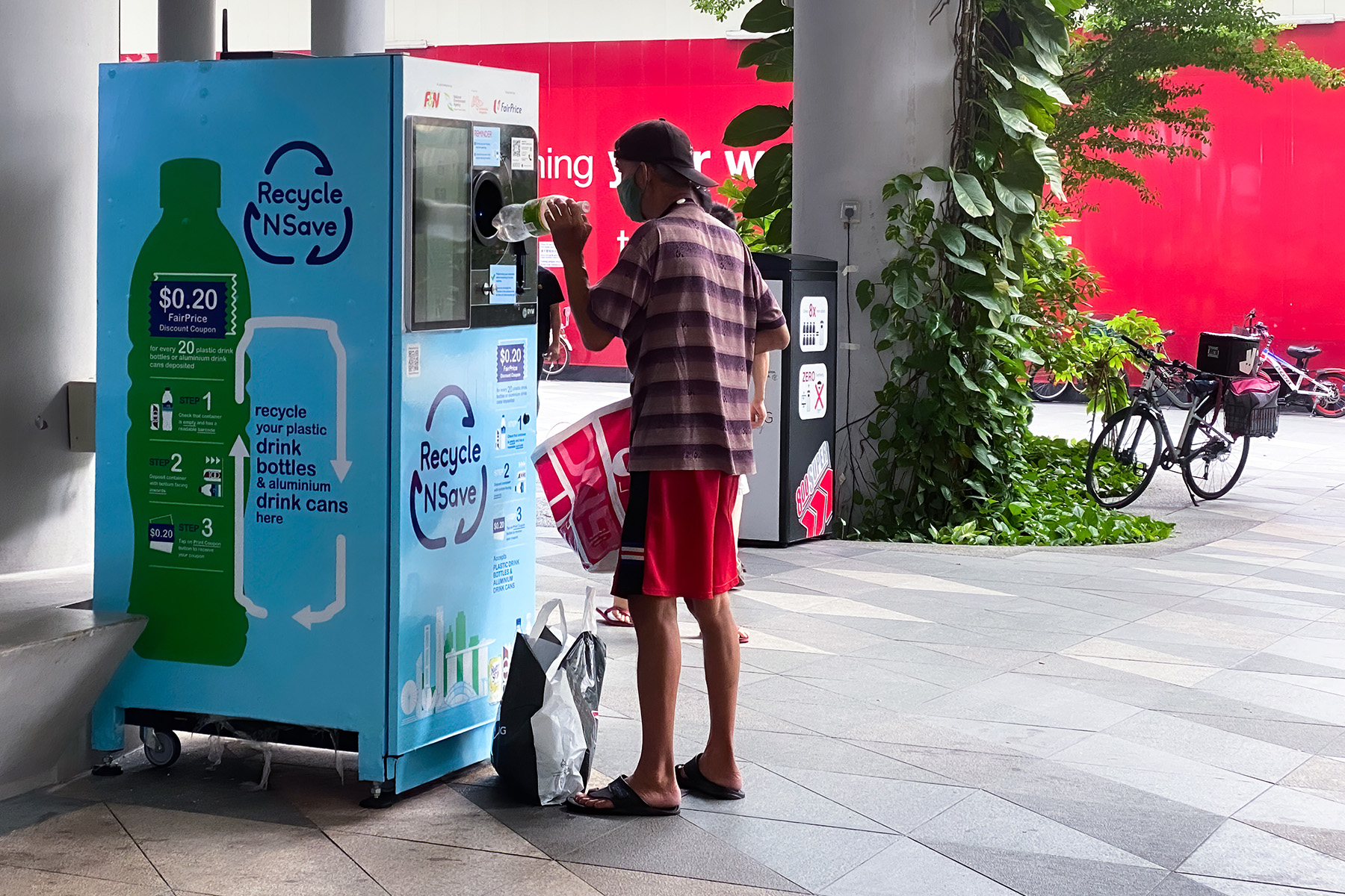 Man recycling plastic bottle in a reverse vending machine in exchange for money.