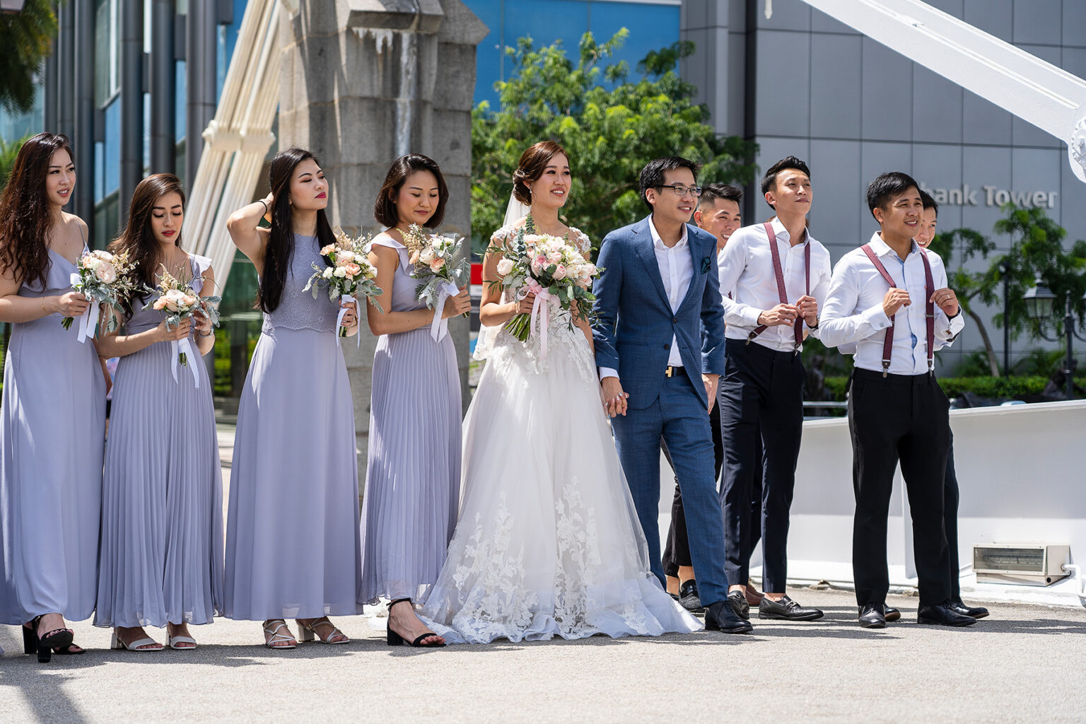 A wedding party posing for a photograph on a sunny day. Bridesmaids in lavender-colored dresses.