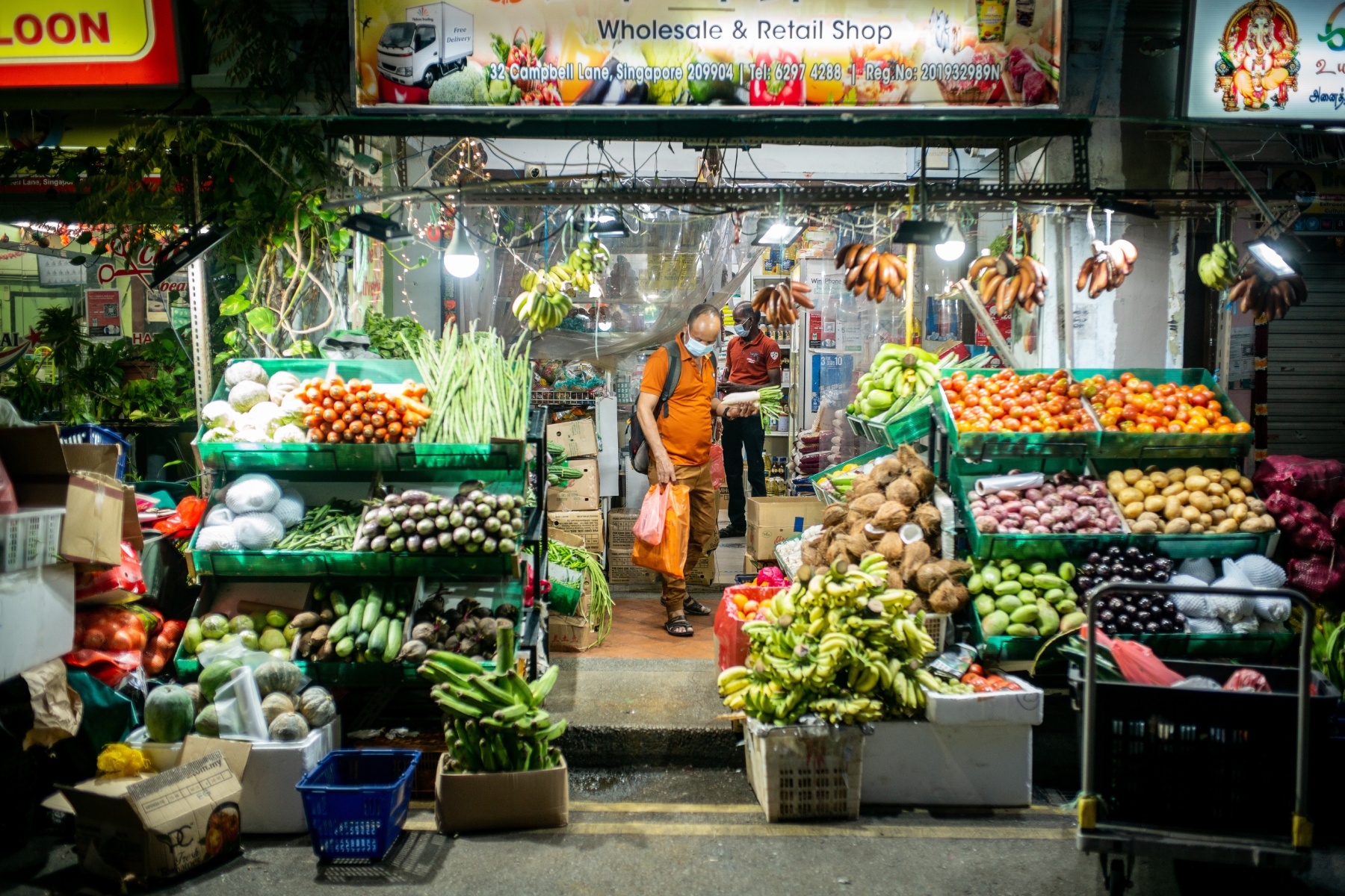 Man exiting vegetable stall at night time 