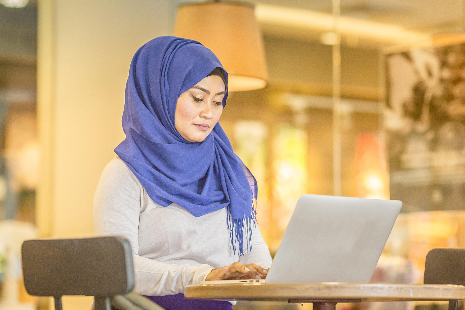 A woman wearing a purple head scarf uses her laptop to find a doctor in Singapore

