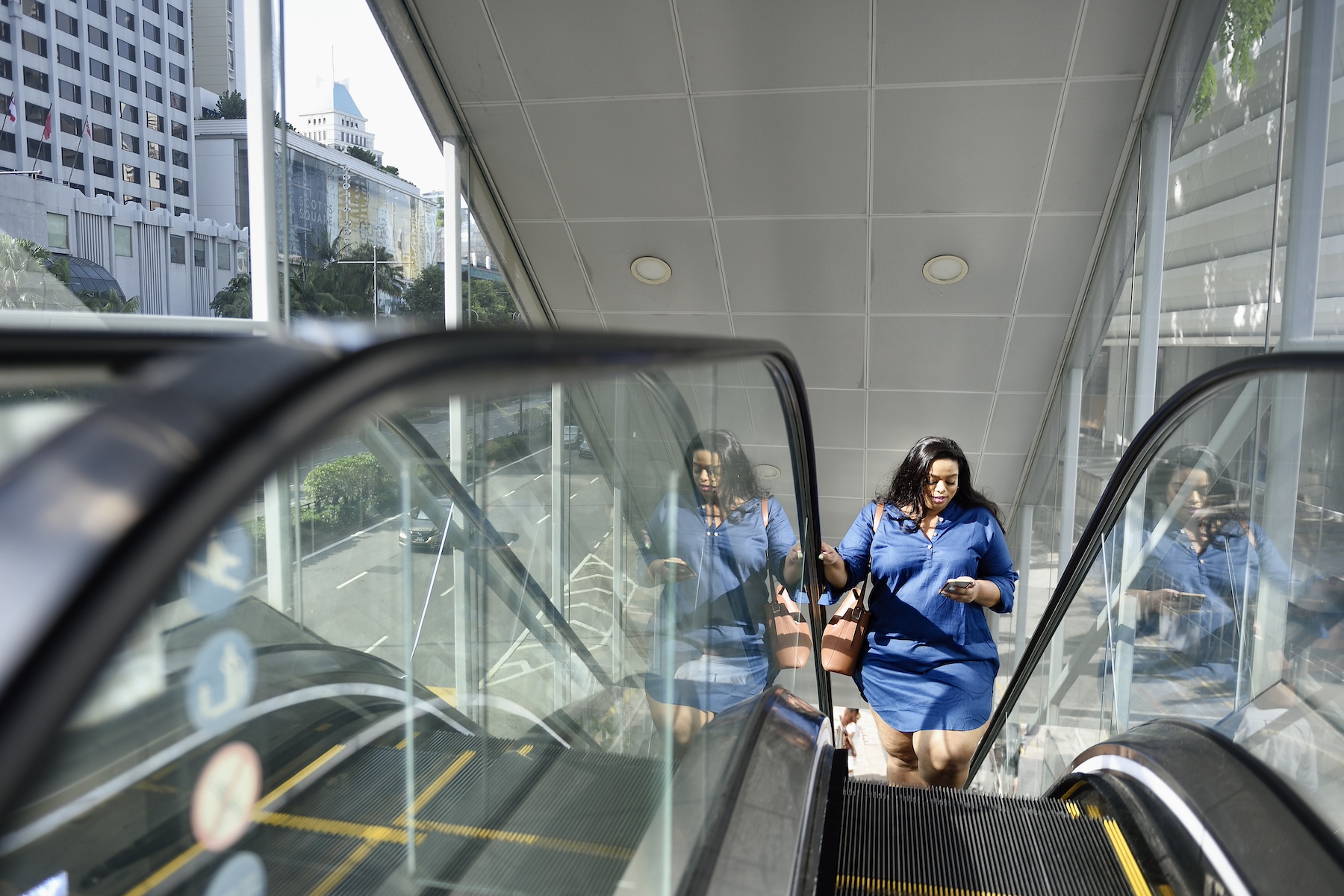 A woman rides the escalator to her office while checking her mobile banking app