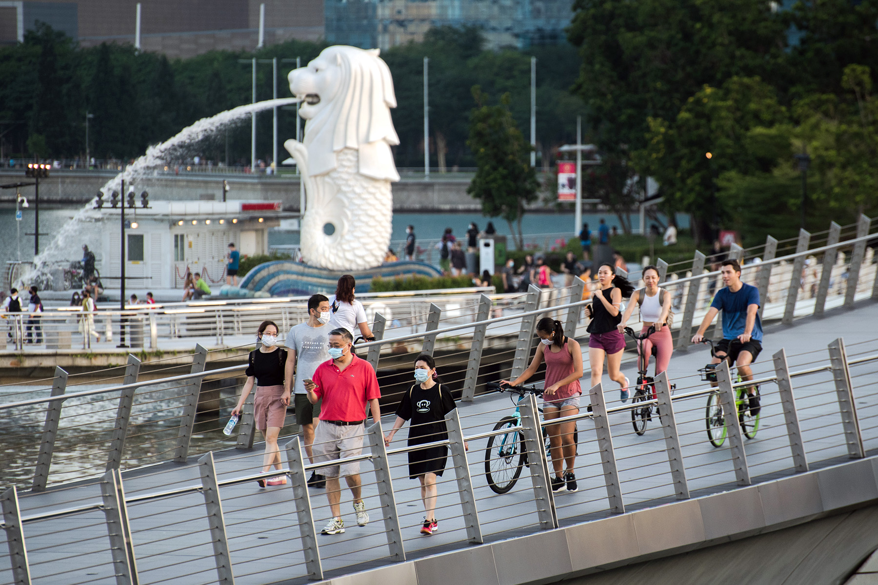 Pedestrians and cyclists share the bridge near the Merlion of Marina Bay in Singapore.