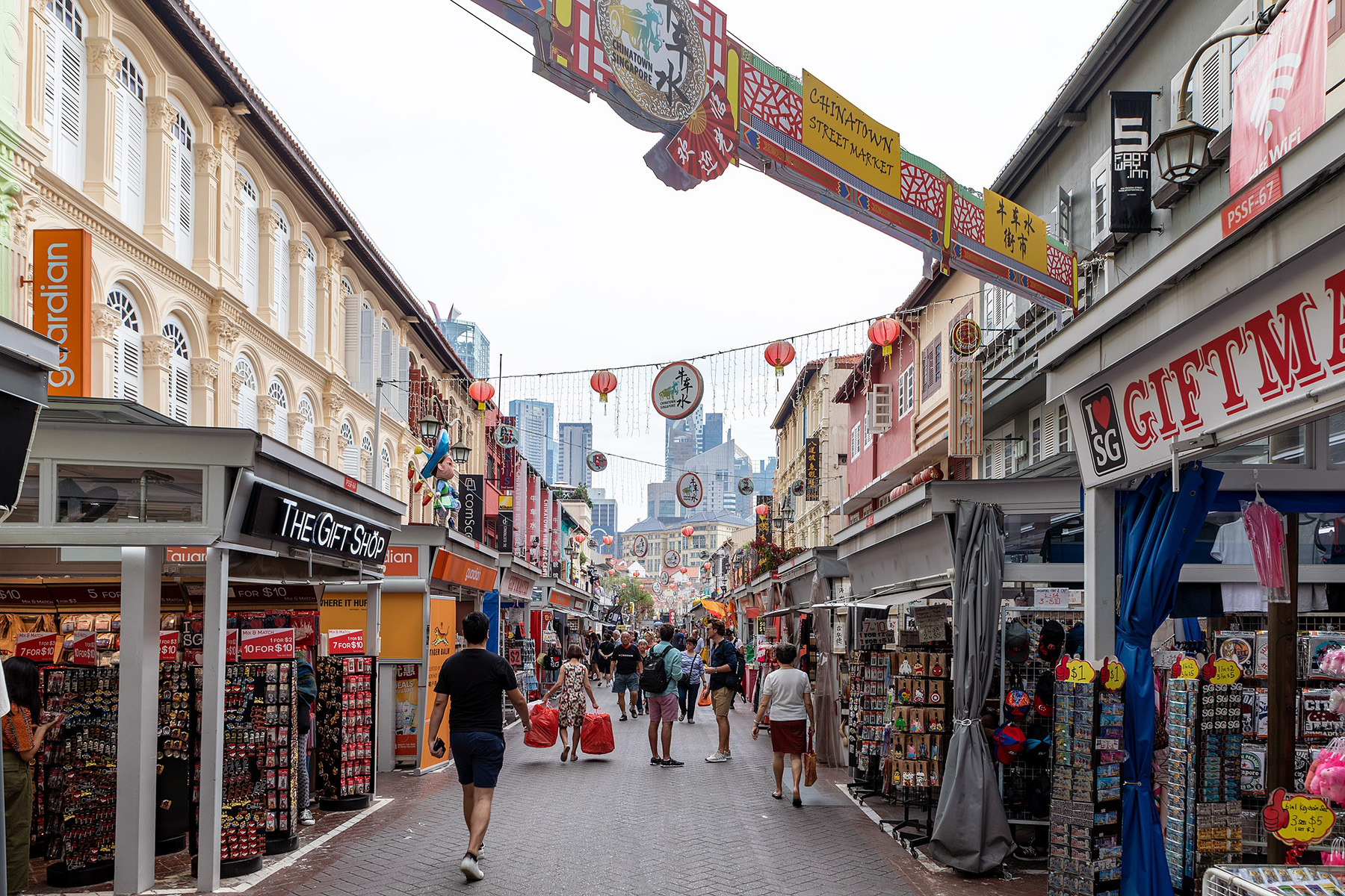 People walking through a quiet shopping alley in Chinatown, Singapore.