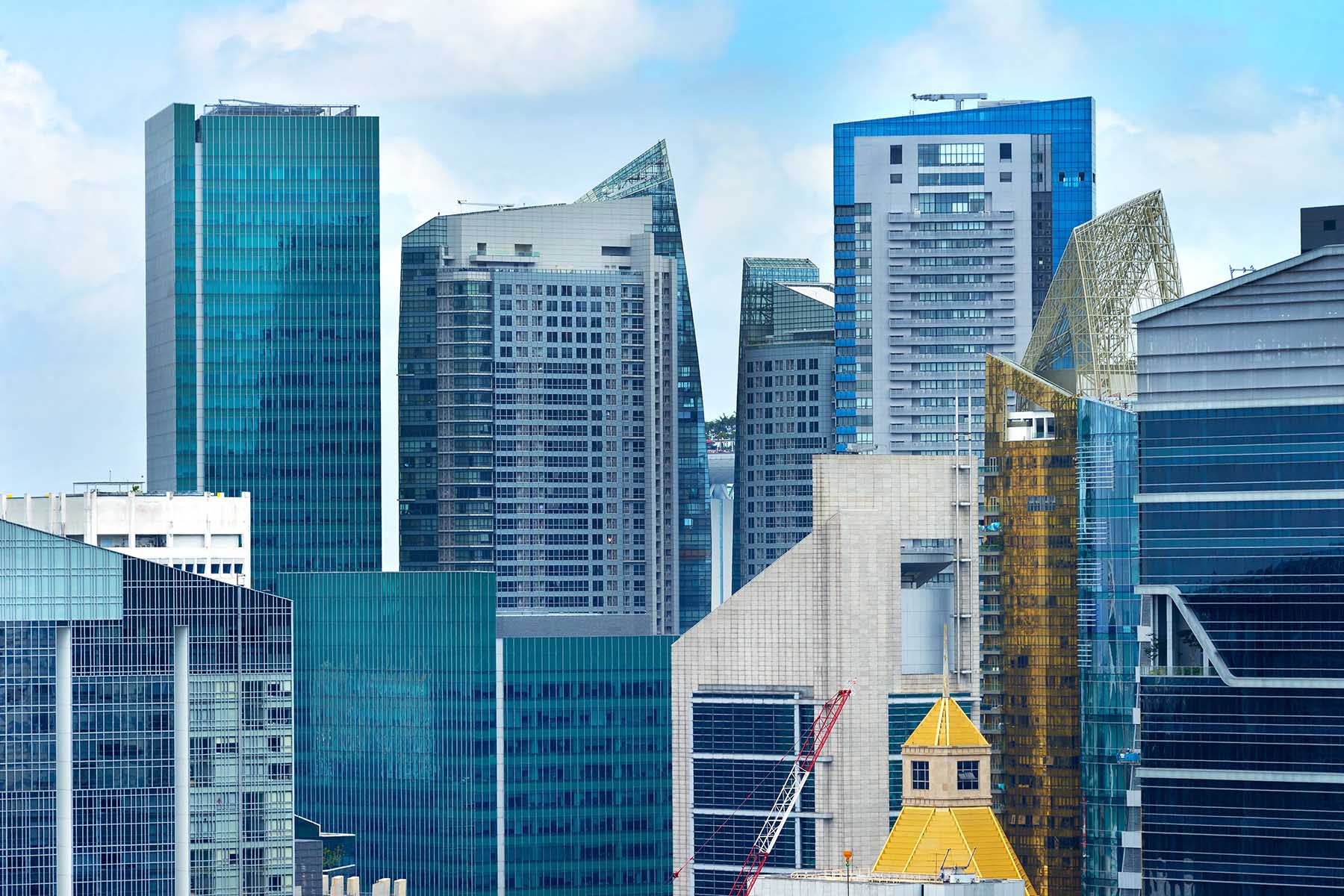 Modern-looking skyscrapers in Downtown Singapore. There is a yellow building in the front, which pops against the blue rest of the image.