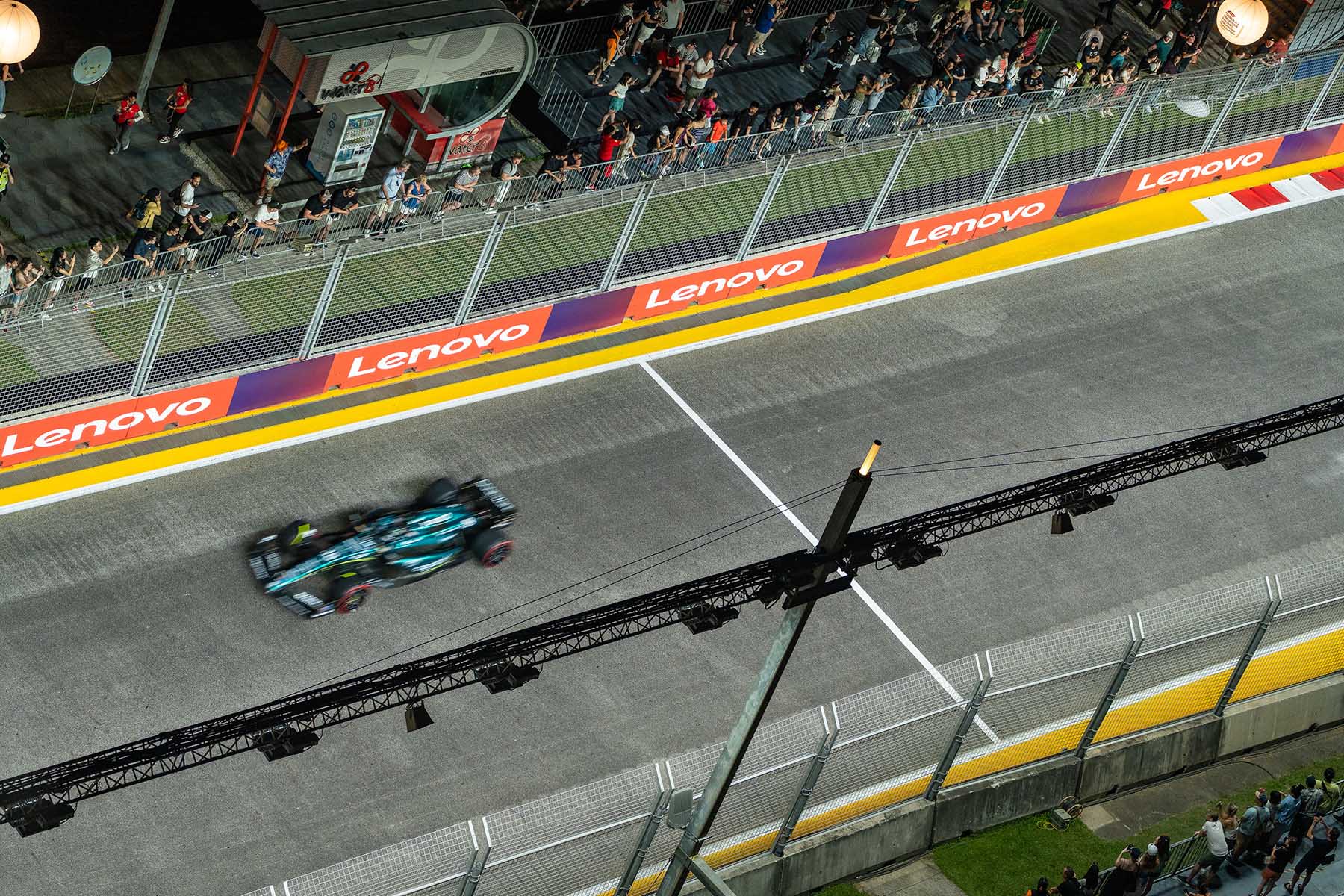 High angle view of spectators watching a F1 car drive by in a practice session at the Marina Bay Street Circuit in Singapore.