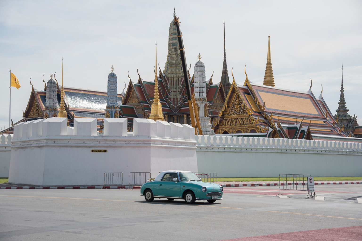 A vintage car driving past the Temple of the Emerald Buddha (Wat Phra Kaew) in Bangkok