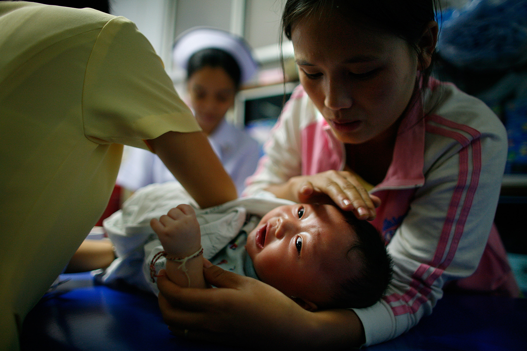 Mother holds her crying baby while the doctor or nurse does a health check, children's healthcare in Thailand
Photo: Paula Bronstein/Getty Images