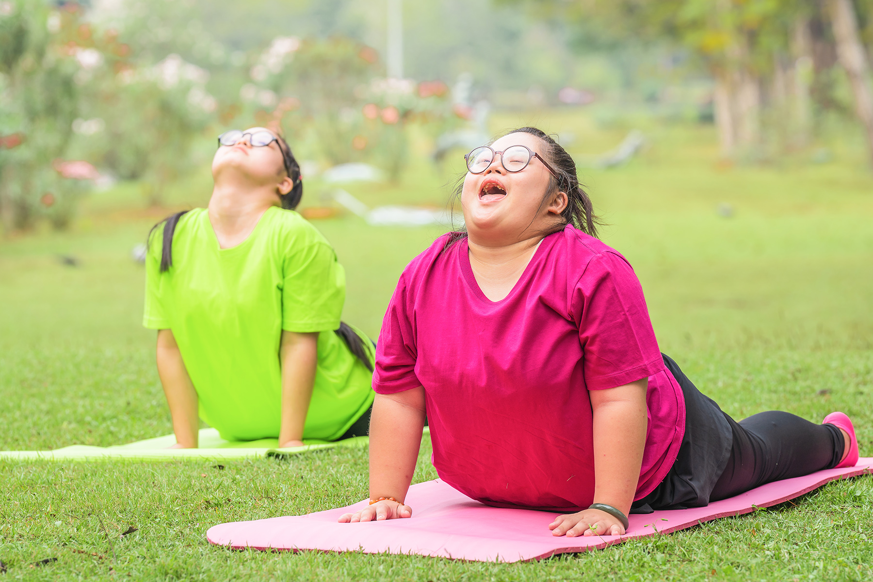 Two teenagers doing yoga in a park to nourish their mental and physical well-being
