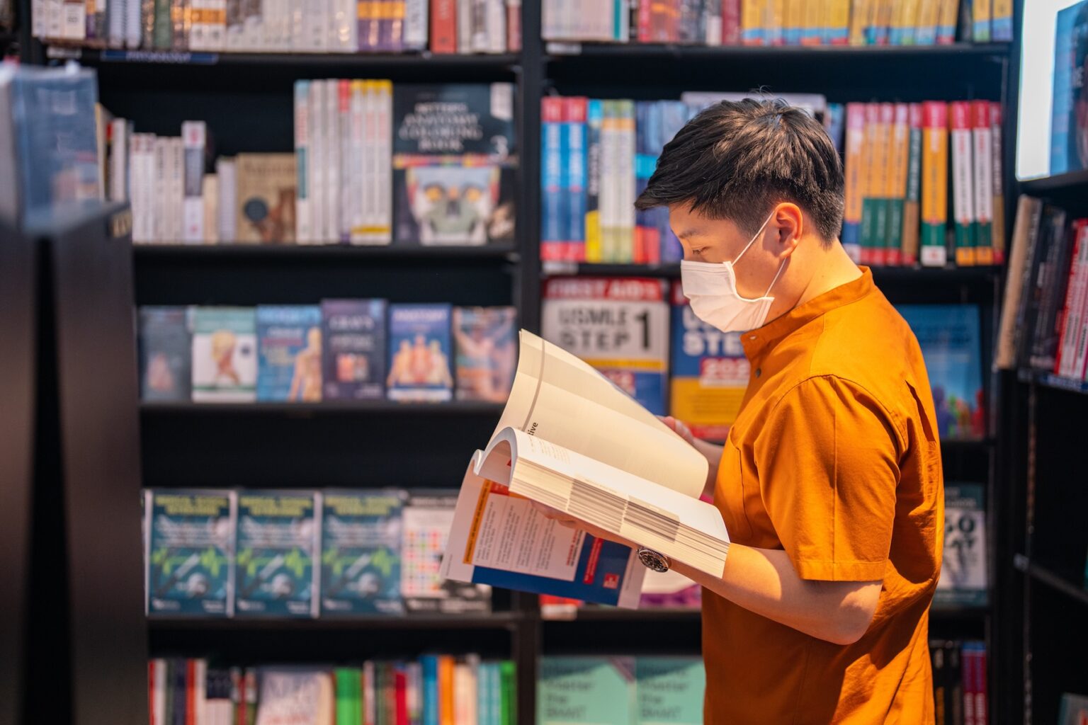 A person stands in the language learning section of a bookstore, studying a book on the Thai language test