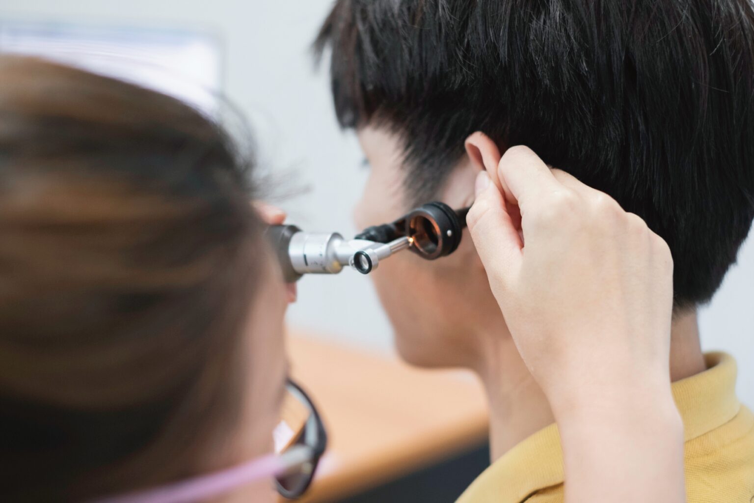 Close-up of a doctor holding an otoscope to a boy's ear in a clinic