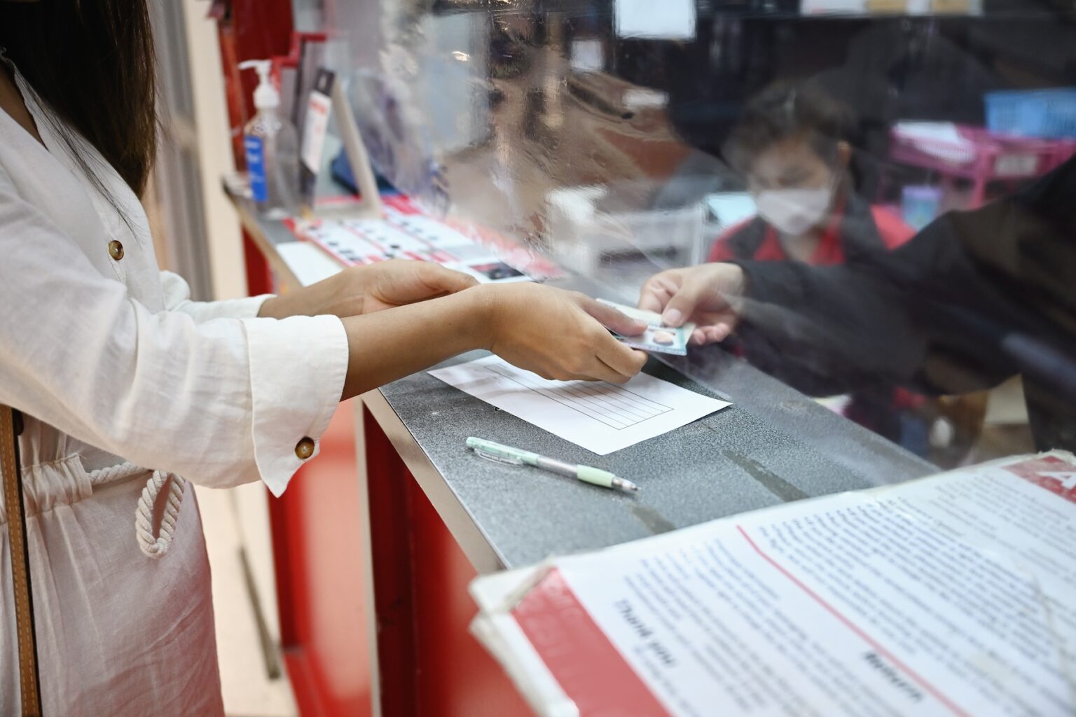 A woman is handing over paperwork to receive her Thai drivers license