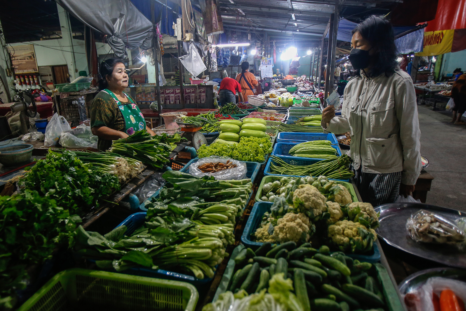 A woman shopping at a vegetable stall at a market