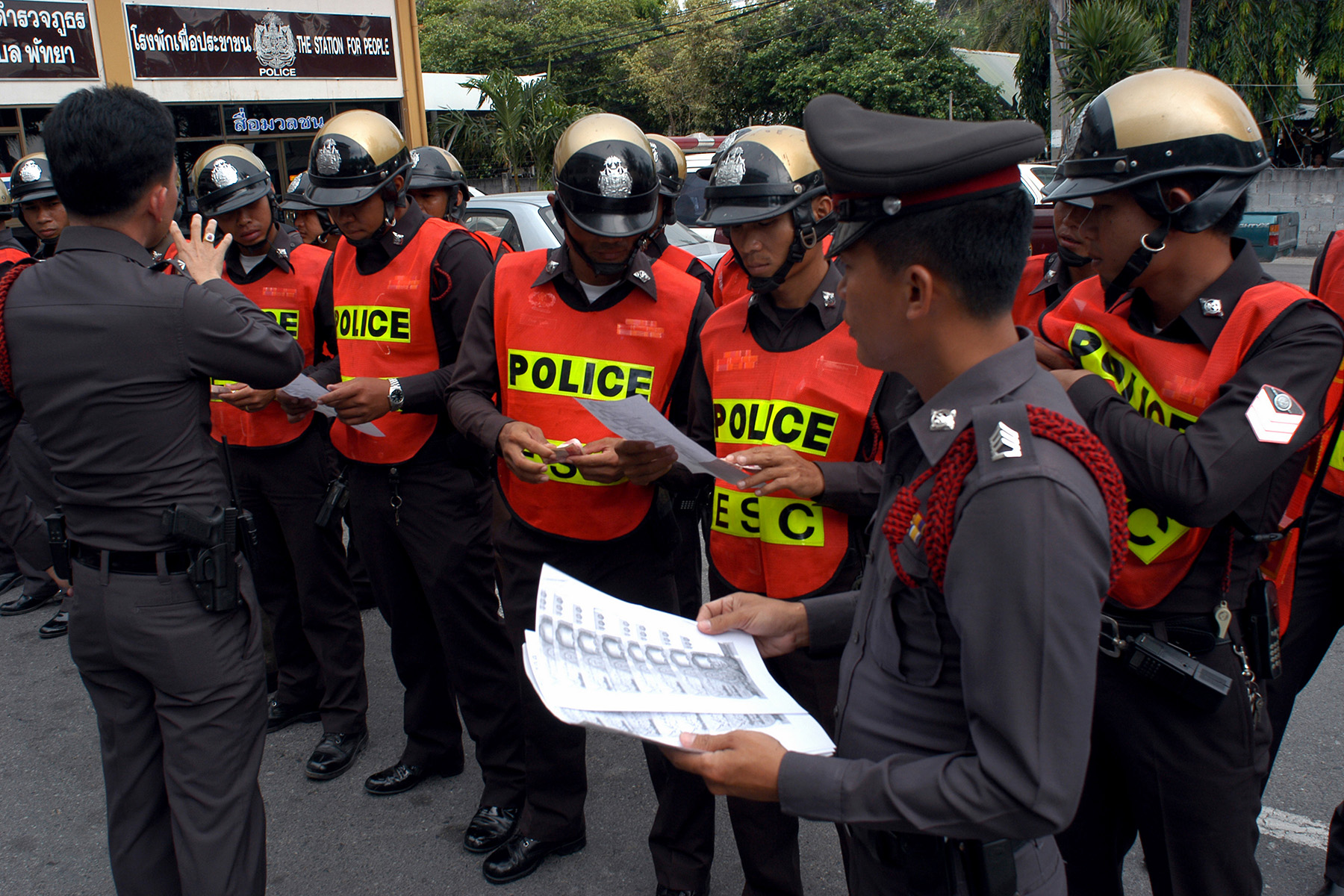 A police briefing, officers in uniforms, high visibility vests and riot helmets
